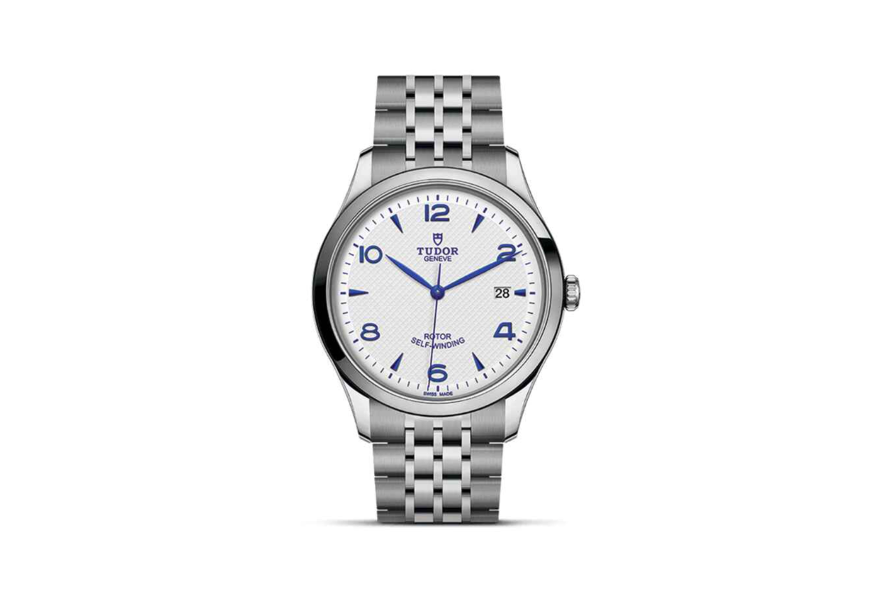 A TUDOR 1926 silver watch with a classic silhouette and navy blue accents on the watchface.