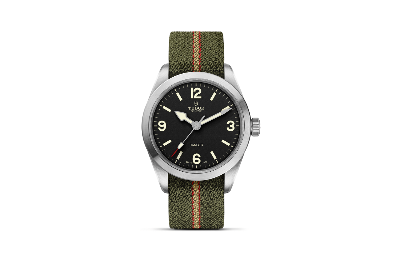 A TUDOR Ranger silver watch with an army green fabric band, a silver bezel, and a black watchface.