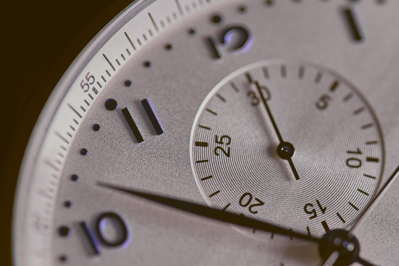 A close-up of a white watch face, showcasing all the tiny details.