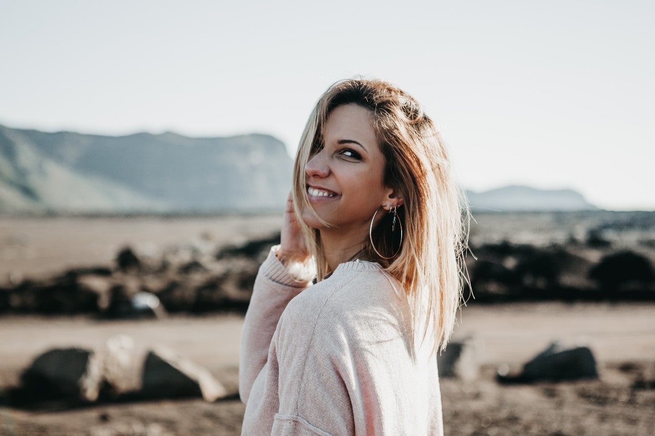 A young woman wearing elegant oversized hoop earrings outside in a rocky area. A young woman wearing elegant oversized hoop earrings outside in a rocky area.