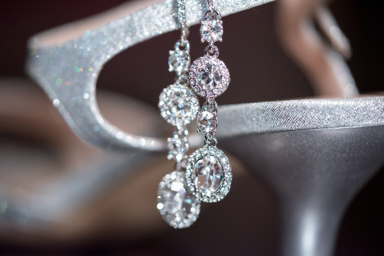 A close-up of a dazzling pair of diamond drop earrings displayed on an elegant shoe. A close-up of a dazzling pair of diamond drop earrings displayed on an elegant shoe.