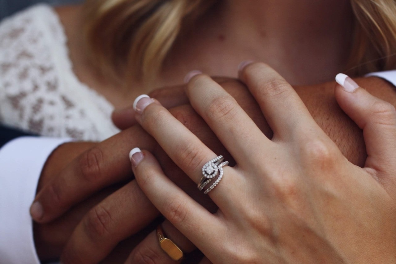 A bride embraces her groom, wearing a modern engagement ring. A bride embraces her groom, wearing a modern engagement ring.