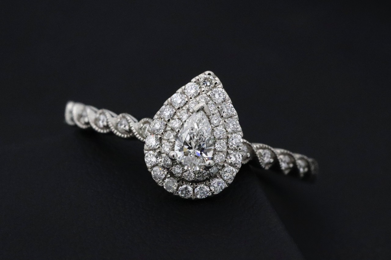 A pear-shaped double halo diamond ring against a black background.