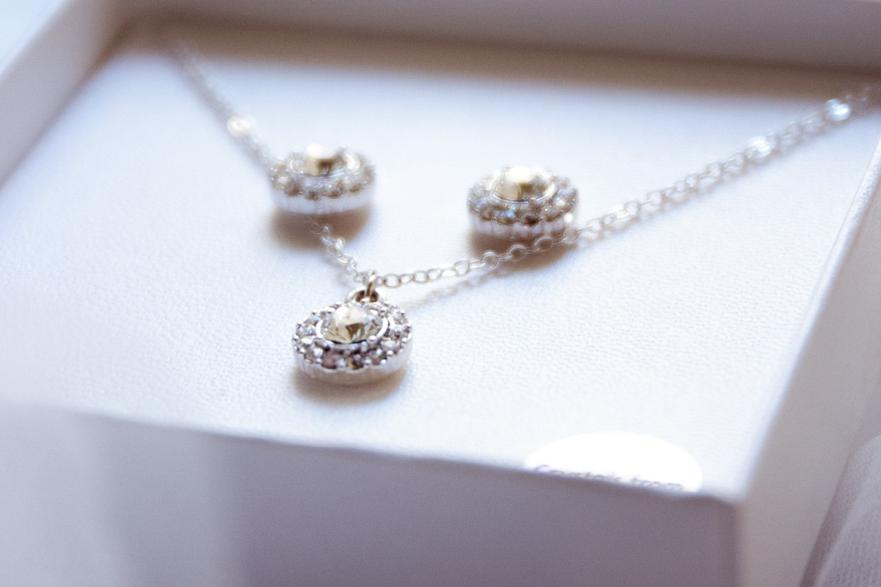 A close-up of a matching diamond earring and necklace set displayed in their box. A close-up of a matching diamond earring and necklace set displayed in their box.